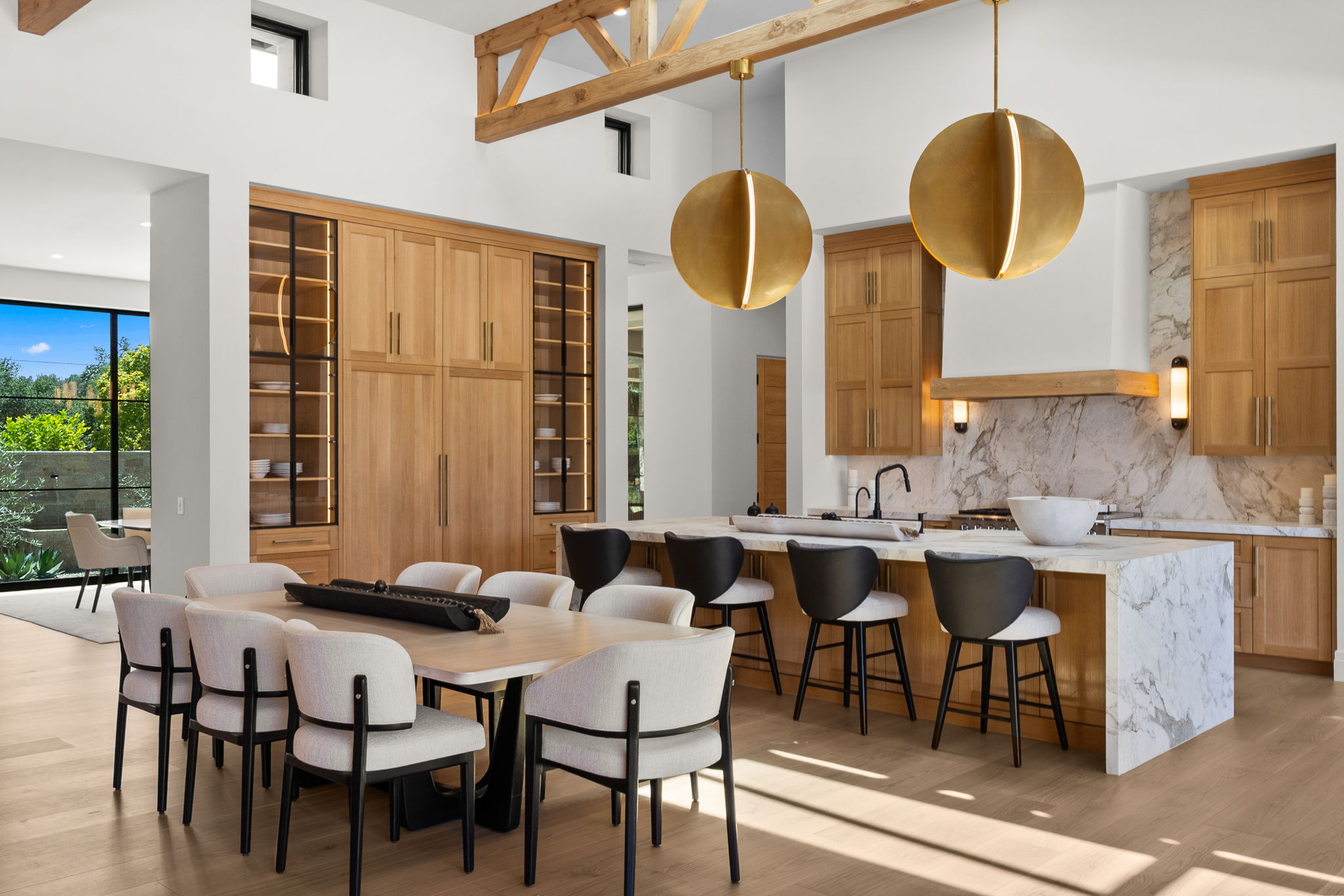 Luxury open-plan kitchen and dining room with marble island and brass pendants — San Diego real estate photography by YonoPro